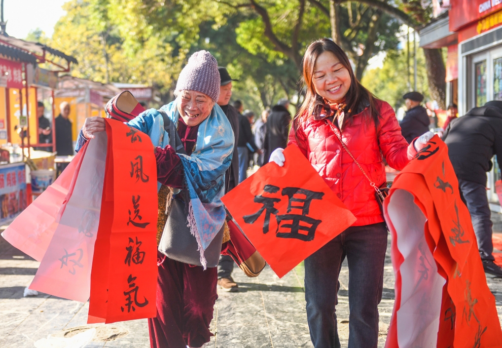 2025年1月13日，在湖南省永州市道縣西洲公園義工崗亭，市民們領到了書法志愿者為大家書寫的春聯(lián)。