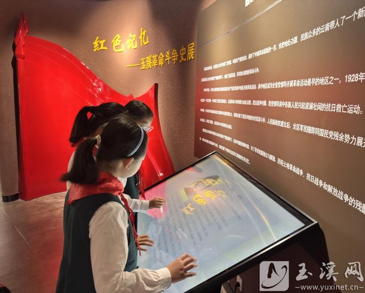 孩子們?cè)诩t色文化展館前駐足，了解玉溪的革命歷史。