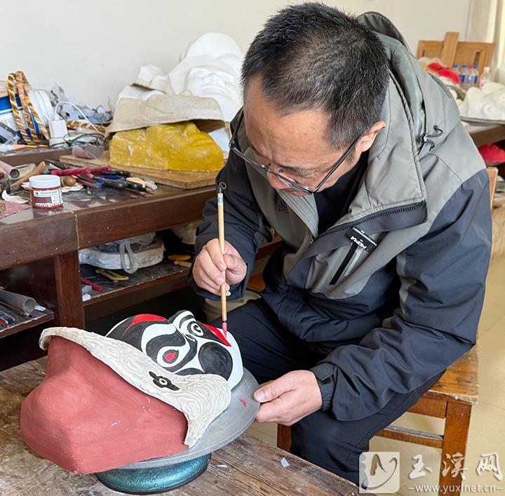 張鴻坤正在用畫筆勾勒關索戲面具。